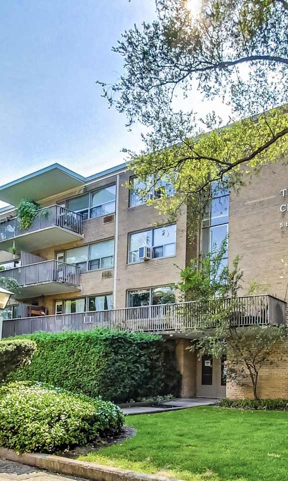 an apartment building with a lawn and trees in front of it