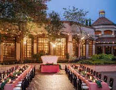 A wedding reception is set up outside a grand building with a long table in the center.