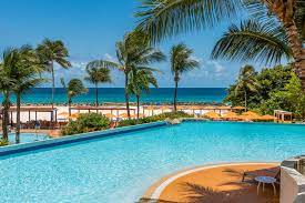 a large pool with palm trees and a beach in the background