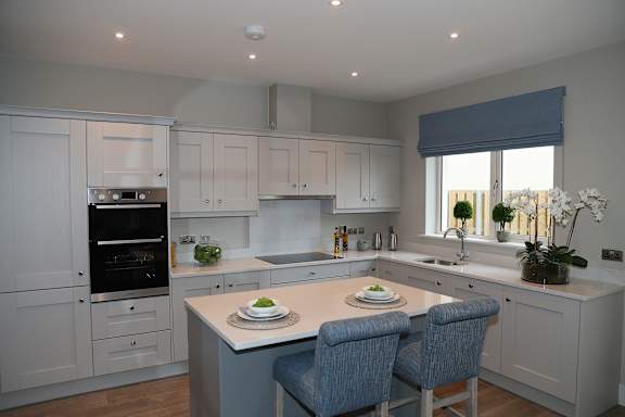 a contemporary kitchen with white cabinets and a white island with blue chairs
