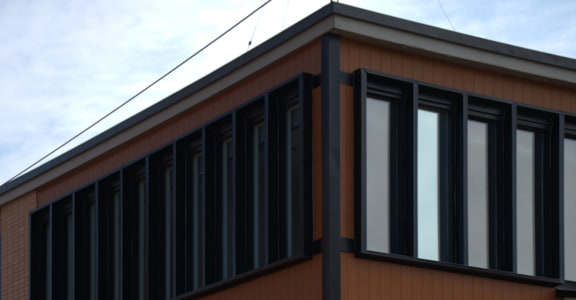 A building with a brown facade and black windows.