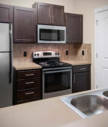 A kitchen with brown cabinets and a black stove top oven.