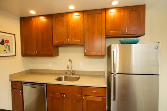 A kitchen with a refrigerator, sink, and cabinets.
