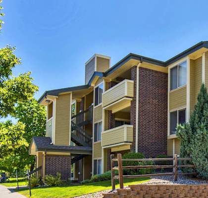 an apartment building with a sidewalk and trees in front of it