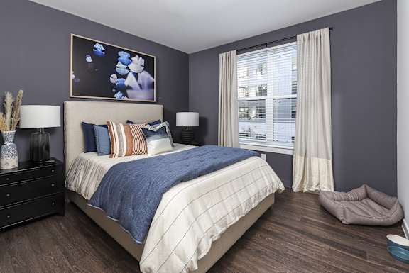 A bedroom with a large bed and a window with curtains.