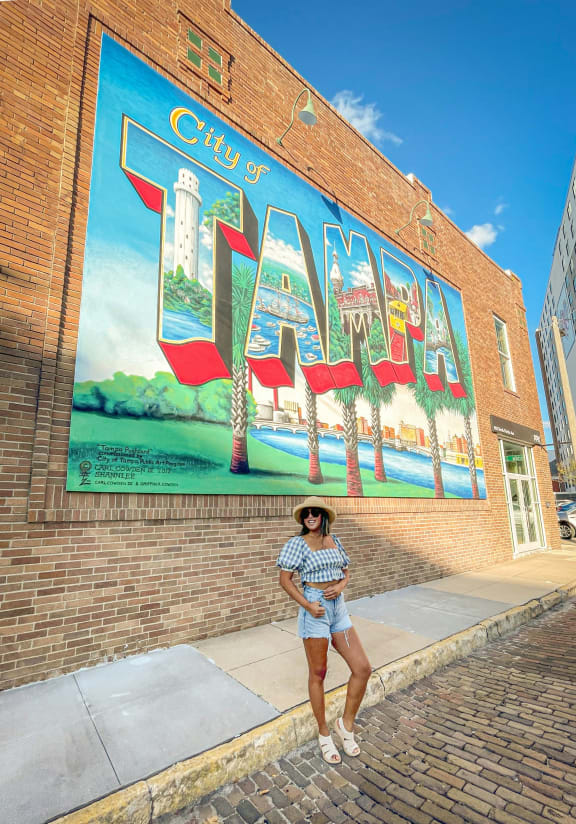 a woman standing in front of a city mural