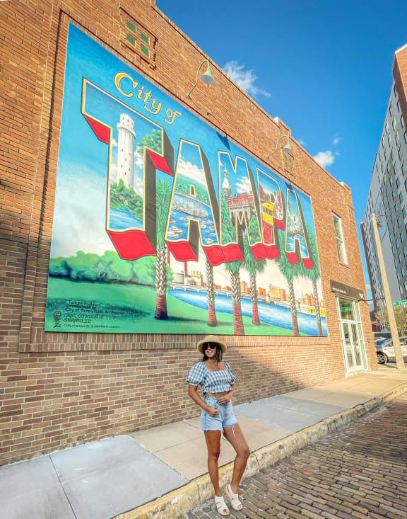 a woman standing in front of a city mural