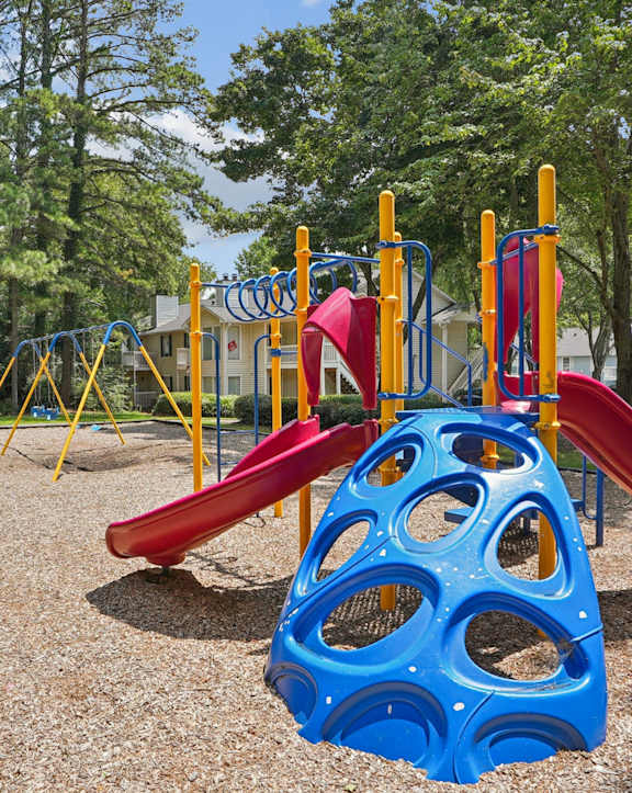 A playground with a blue slide and a red slide.