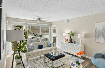 A living room with a white couch, a blue chair, and a painting on the wall.