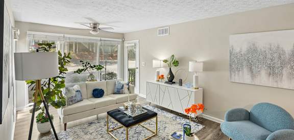 A living room with a white couch, a blue chair, and a painting on the wall.