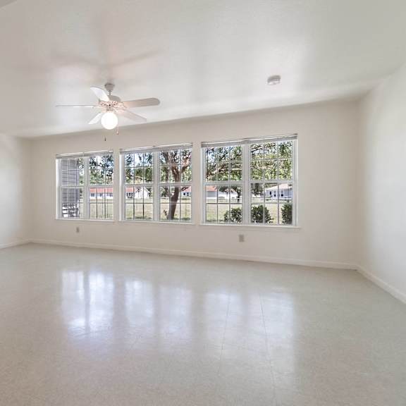 an empty living room with large windows and a ceiling fan at Huntington Village **, Warner Robins, Georgia