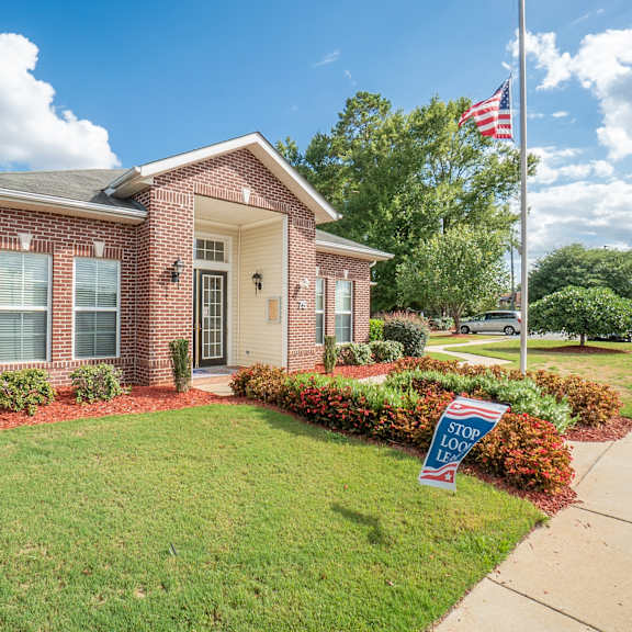 a small brick house with an flag and a sign in front of it at Huntington Village **, Warner Robins, Georgia
