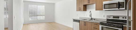 an empty kitchen with wood flooring and stainless steel appliances