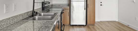 a kitchen with granite counter tops and a stainless steel refrigerator