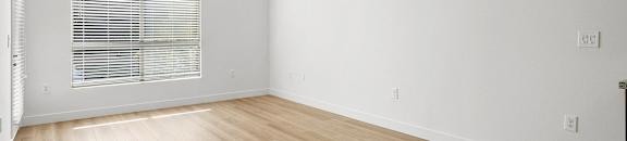 an empty room with wood floors and a window