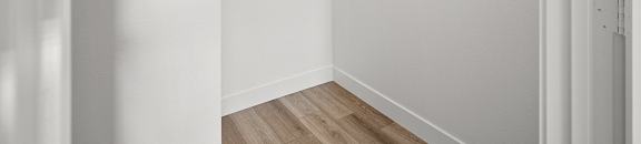 an empty room with white walls and a white closet with a rack on the wall