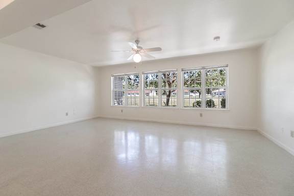 an empty living room with large windows and a ceiling fan at Huntington Village **, Warner Robins, 31098