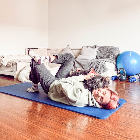 woman on a yoga mat stretching with her dog