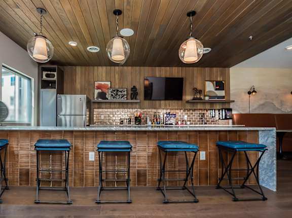 A bar with blue stools and a wooden ceiling.