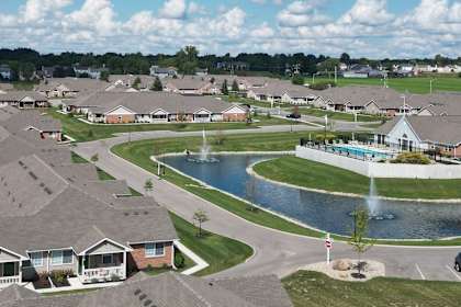 A bird's eye view of a residential neighborhood with houses, a pond, and a fountain.