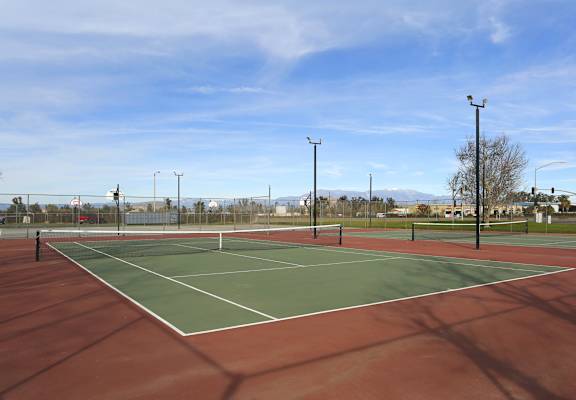 A tennis court with a net and light poles.