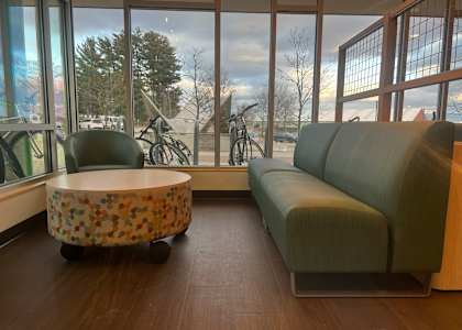 A round table with a patterned top sits in front of a window with a view of a bicycle and trees outside.