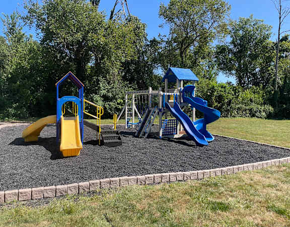 a playground with two slides and a swing set on a sunny day