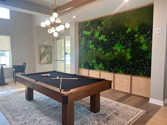 A pool table in a room with a green wallpaper.