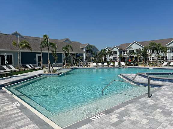 A large swimming pool with a slide and a building in the background.