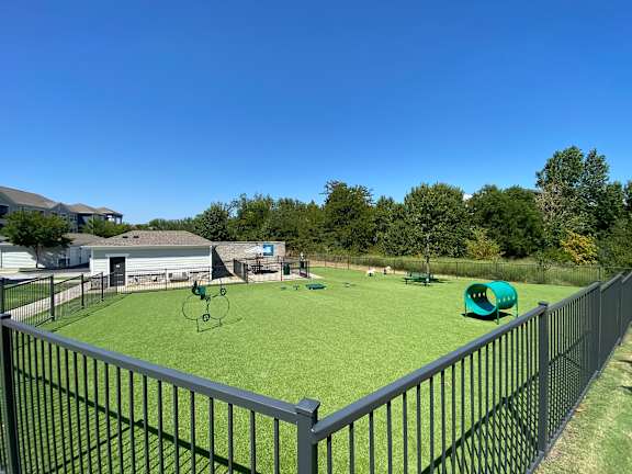 a fenced in backyard with a dog park and agility course at Watermark at Steele Crossing, Arkansas