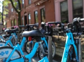 a row of blue bikes parked in front of a building