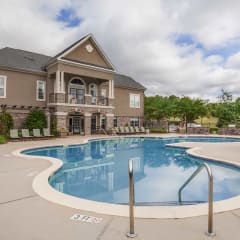 A large outdoor swimming pool with a building in the background.at Carrington Place at Wildewood, Columbia, SC