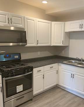 A kitchen with white cabinets and a black refrigerator.