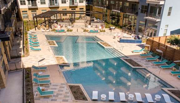 A large swimming pool surrounded by lounge chairs and umbrellas.