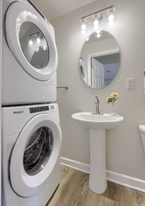 A white washing machine and sink in a laundry room.