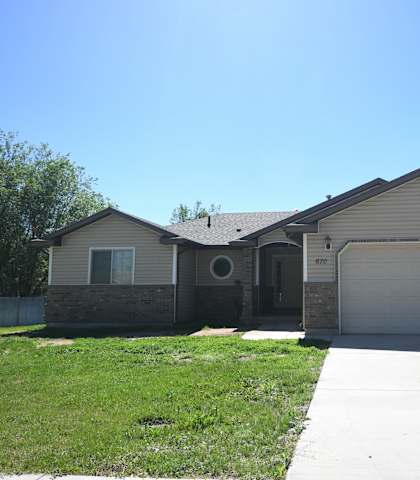 a beige house with a garage door and a lawn