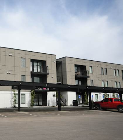 an apartment building with a parking lot and a red car
