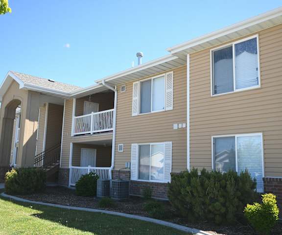the exterior of an apartment building with tan siding and a balcony