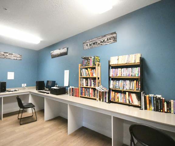 a library with two long desks with bookshelves and computers
