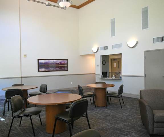 a large room with tables and chairs and a kitchen