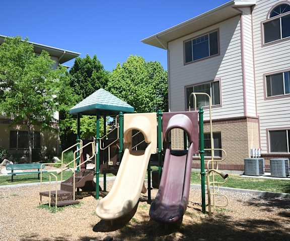 a playground with two slides in front of a house