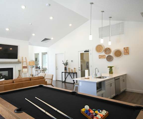 a living room with a pool table and a kitchen