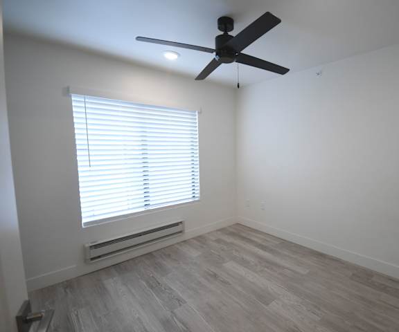 an empty room with a ceiling fan and a window