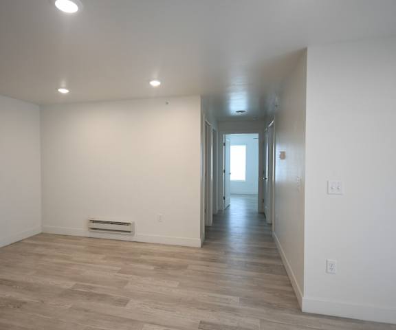 a living room and hallway with white walls and wood flooring