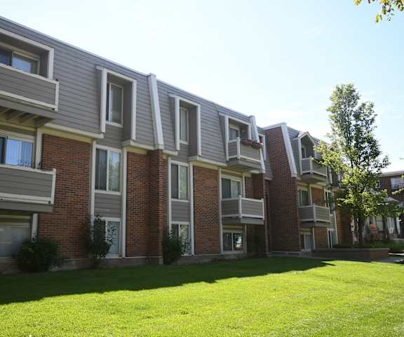 an apartment building with a green yard in front of it