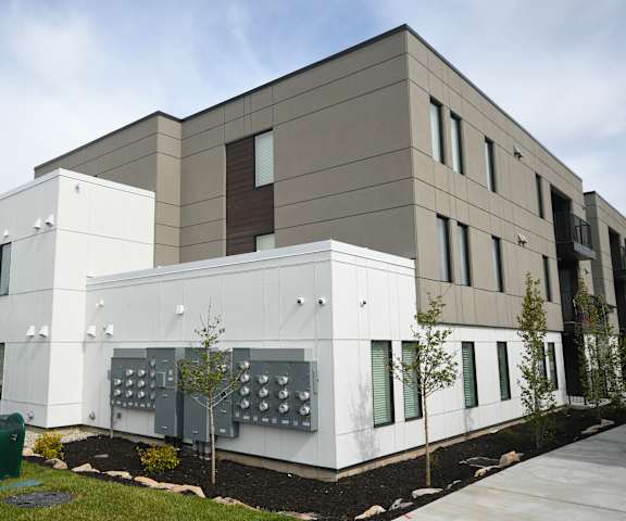 a white building with a sidewalk and trees in front of it