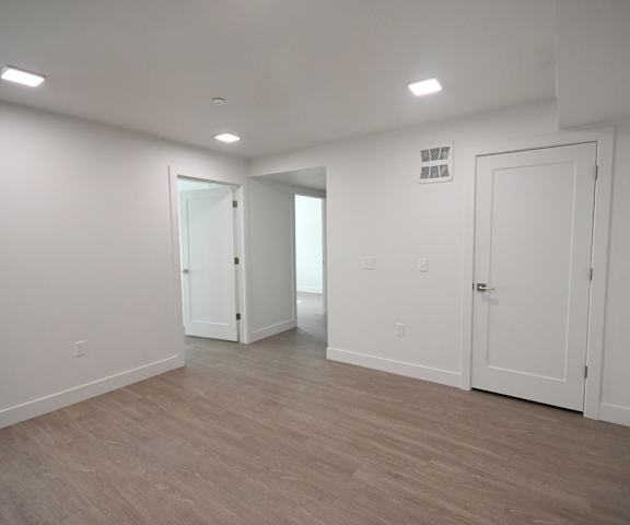 an empty living room with white walls and a wooden floor