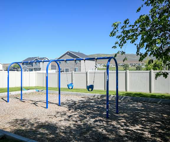 a blue swing set in a park with houses in the background