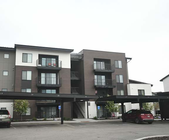 the apartment building has a parking lot with cars in front of it