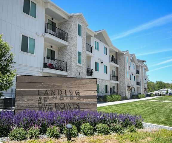 a sign in front of an apartment building with purple flowers